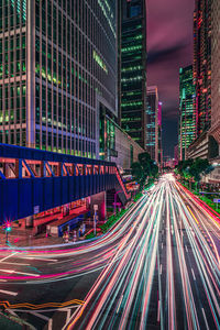 Light trails on city street by buildings at night