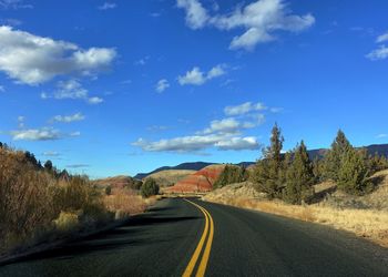 Empty road amidst landscape against sky