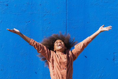 Happy young woman standing against wall