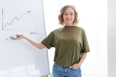 Portrait of a smiling young woman standing against wall