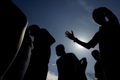 Low angle silhouette people standing against sky during sunset