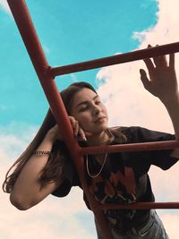 Low angle view of woman lying on ladder against sky