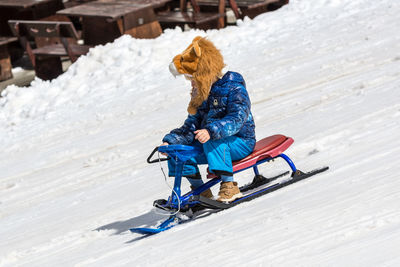 Full length of boy sitting on snow