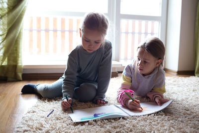 Cute sibling writing in drawing book at home