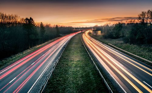 Light trails on road against sky at sunset