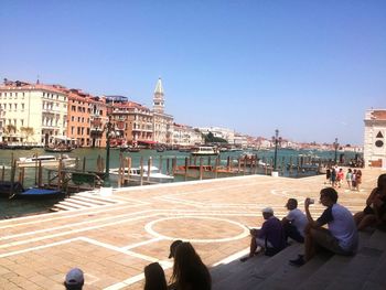 People sitting in town square against clear sky