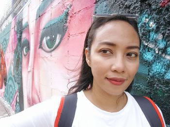 Portrait of beautiful young woman against wall