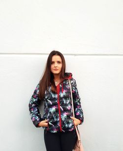 Portrait of a beautiful young woman standing against wall