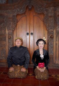 Portrait of young woman sitting on wooden door