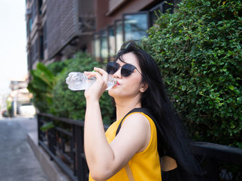 Portrait of woman holding sunglasses outdoors