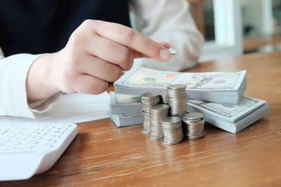 Close-up of hand holding coins on table