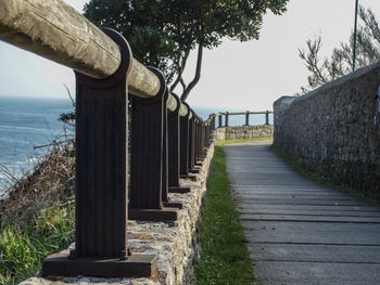 Walkway by sea against sky