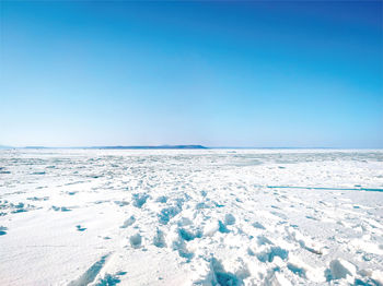 Scenic view of snow covered landscape against clear blue sky