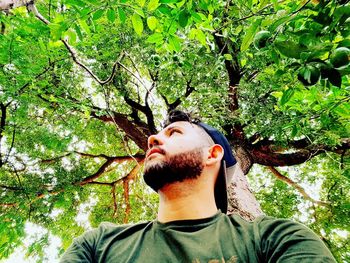 Portrait of young man against leaves in forest