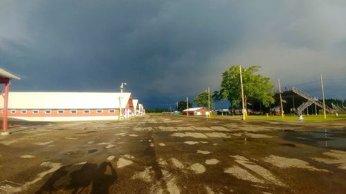 Empty road by buildings in city against sky