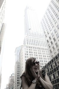 Happy surprised woman against buildings in city