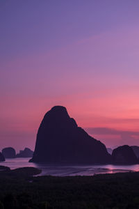 Silhouette rocks on beach against sky during sunset