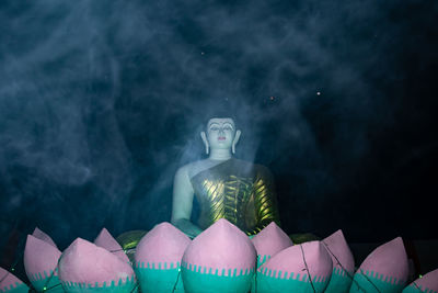 Statue against illuminated temple