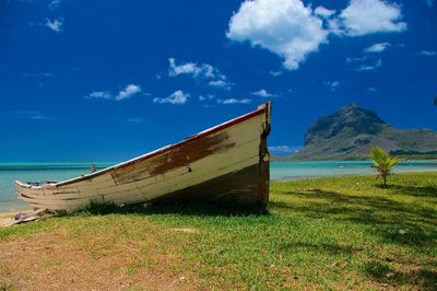 Abandoned boat on beach against sky