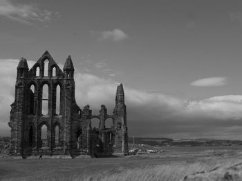 Old ruins of building on field against sky