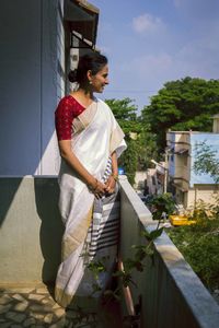 Woman standing by tree against sky