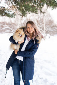 Portrait of woman with dog on snow