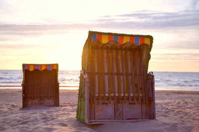 Wooden posts on beach against sky during sunset