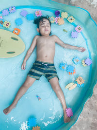 High angle view of shirtless boy lying in swimming pool