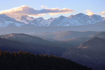 View of the forest and snowy mountain peaks on a hazy winter evening in the colorado rocky mountains