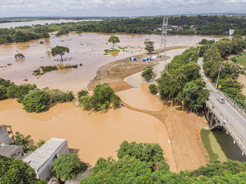 River flooding due to rain causes large mud next to a dam that prevents the rivers from meeting 