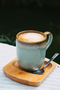 Cup of coffee latte in green poetry mug on old wooden background in the morning sunlight