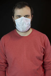 Portrait of young man standing against black background