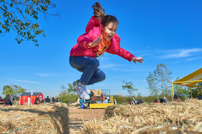Pretty girl jumping over the hay stacks at a farm fair on halloween