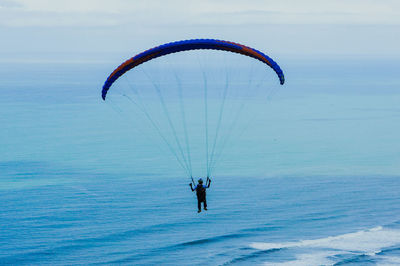 Man paragliding over sea against sky