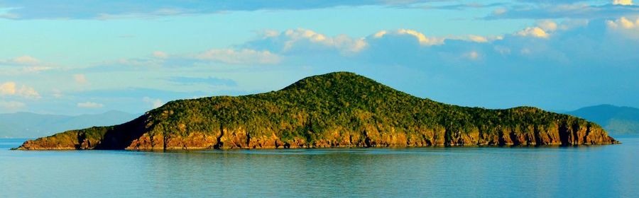 Scenic view of mountain by sea against sky