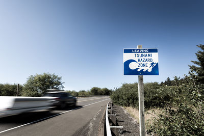 Road sign against clear blue sky