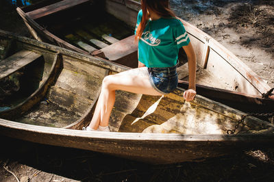 Young woman sitting in boat at lakeshore