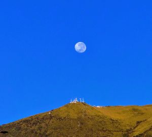 Low angle view of moon against clear blue sky