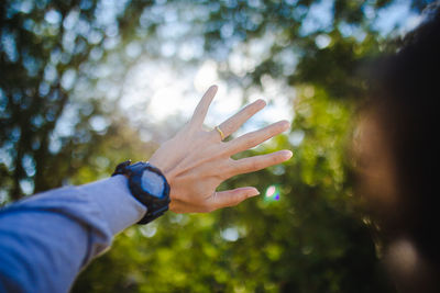 Close-up of person shielding eyes against trees 