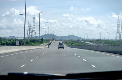 Cars on road against sky seen through car windshield