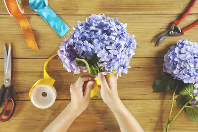 Cropped image of woman making bouquet at wooden table