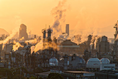 Smoke emitting from factory against sky