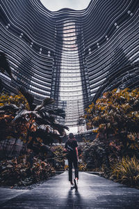 Rear view of man walking on street amidst buildings