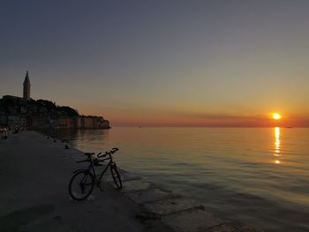 Scenic view of sea by buildings against sky during sunset