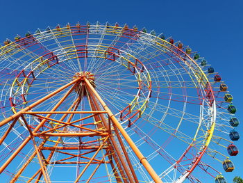 Low angle view of ferris wheel against blue sky