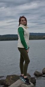 Portrait of woman standing on rock by sea against sky