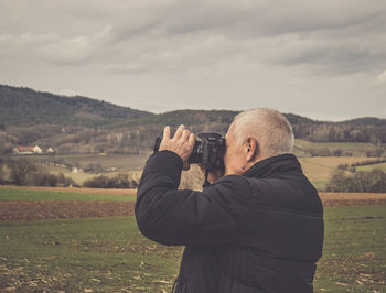 Rear view of man photographing on landscape