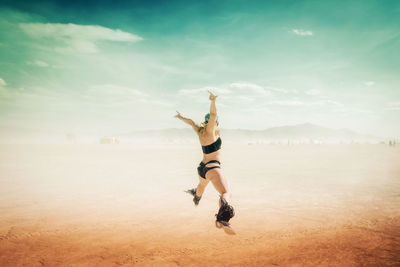 Full length of man jumping at beach against sky