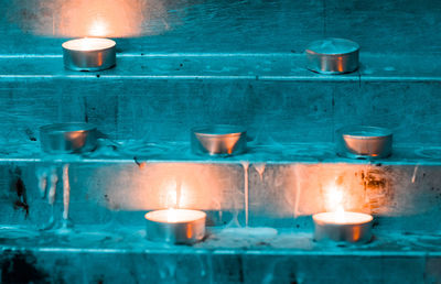 Close-up of illuminated tea light candles against wall