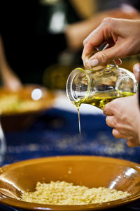 Close-up of man pouring oil in bowl